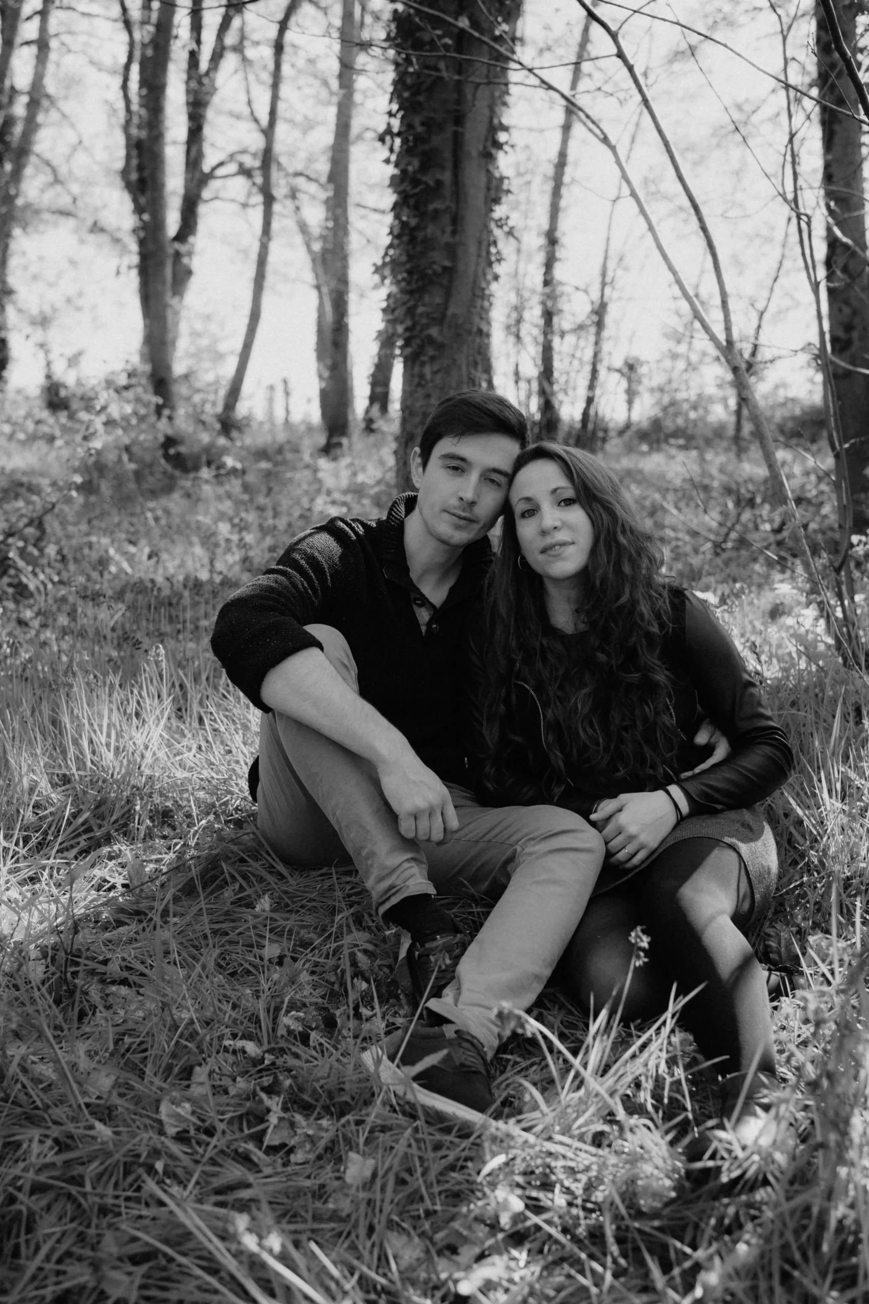 Séance d'engagement. Photographe Mariage. Couple de futurs mariés dans une forêt. Photographie en noir et blanc.